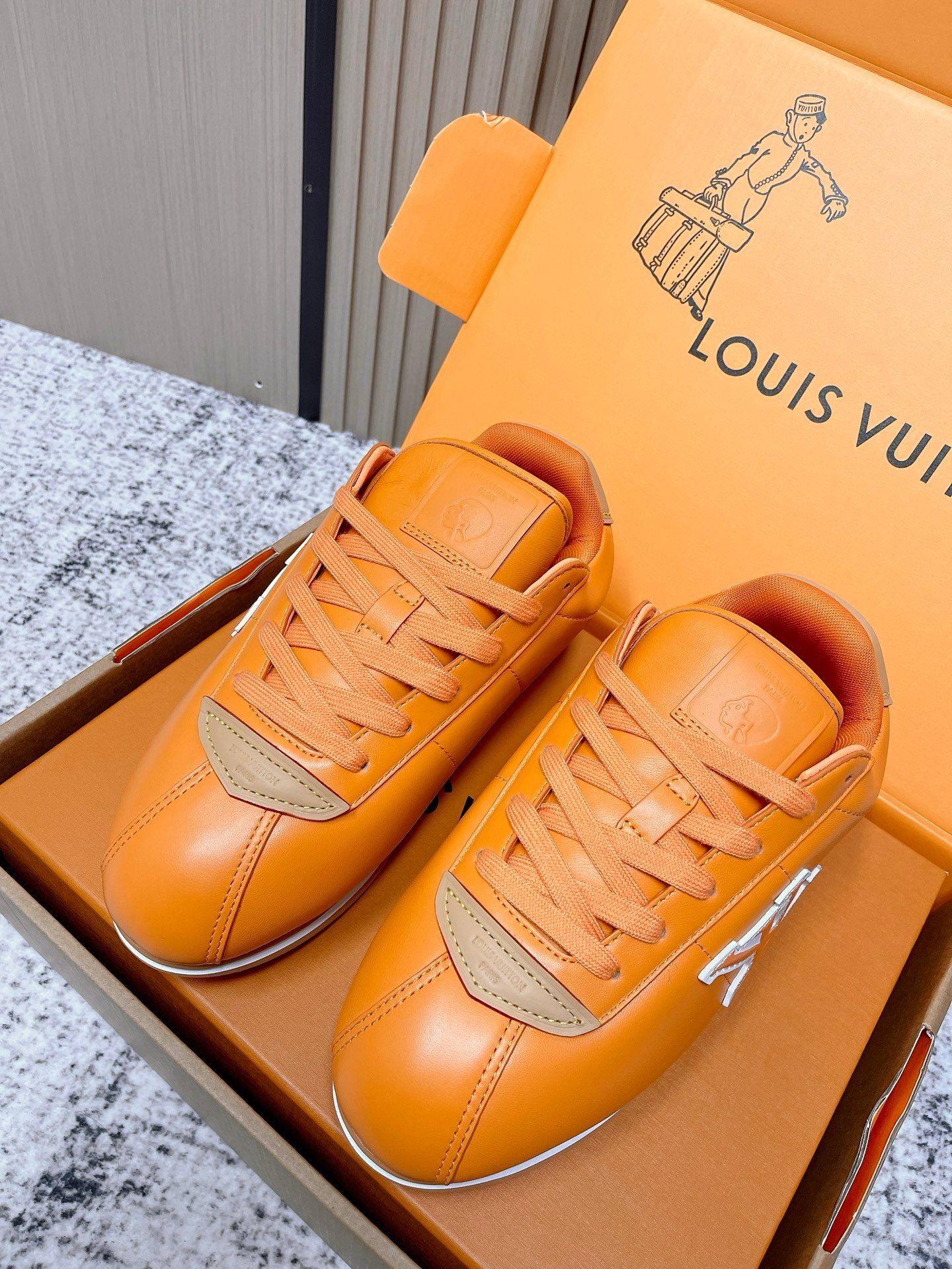 這款 LV 精品仿製 Charlie 橘棕運動鞋，以 Louis Vuitton 經典低筒輪廓結合亮面小牛皮質感打造。鮮明的橘棕色調展現活力與高級感，搭配米色皮革拼接與白色 LV 立體標誌，造型層次分明。鞋舌壓印品牌標誌，展現低調奢華細節。橡膠鞋底輕量防滑，避震性能優異，穿著舒適穩定。此款精品仿製鞋款比例精準、縫線平整，細節完全對標原版工藝，兼具時尚與實穿性。無論搭配休閒牛仔、運動長褲或西裝外套，都能展現獨特品味。本站提供全程追蹤配送、退換保障與秘密包裝，讓您安心入手高品質精品級仿製鞋款。